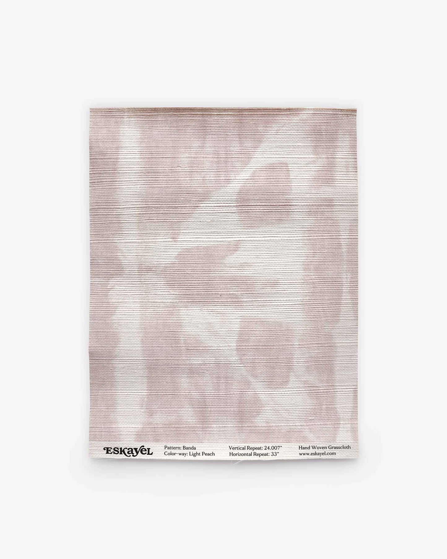 A rectangular sample of Banda Grasscloth||Light Peach features a pale, abstract pattern in soft peach tones reminiscent of shibori tie-dye. Labeled “Eskayel” at the bottom with design and weave details, it offers perfect inspiration for custom wallpaper or luxury grasscloth wallpaper designs.