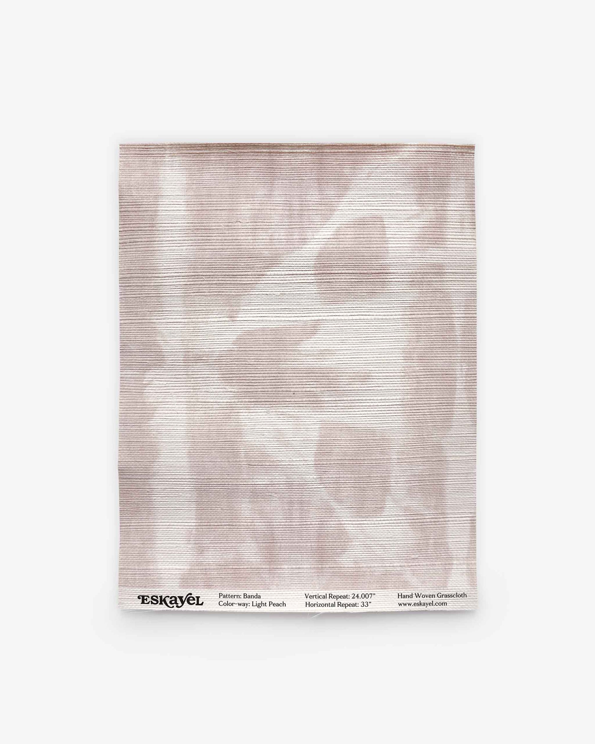A rectangular sample of Banda Grasscloth||Light Peach features a pale, abstract pattern in soft peach tones reminiscent of shibori tie-dye. Labeled “Eskayel” at the bottom with design and weave details, it offers perfect inspiration for custom wallpaper or luxury grasscloth wallpaper designs.