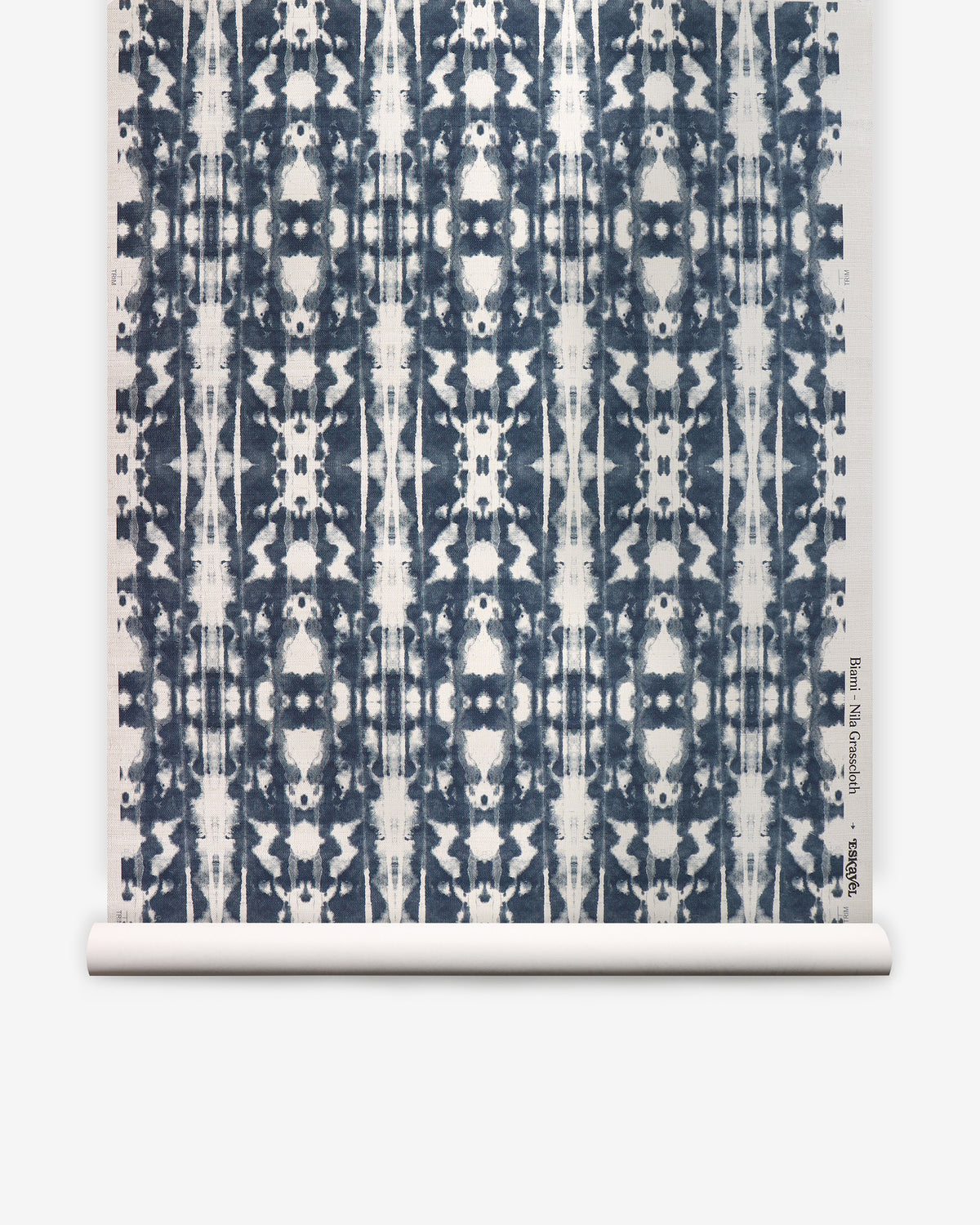 A roll of Biami Grasscloth||Nila wallpaper featuring a geometric, symmetrical navy blue on white pattern with a tie-dye effect reminiscent of woven textiles.