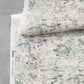 A roll of Bosky Toile Grasscloth in Chloros, featuring a cream-colored luxury sisal background with a green ink sketch of tropical trees and foliage.