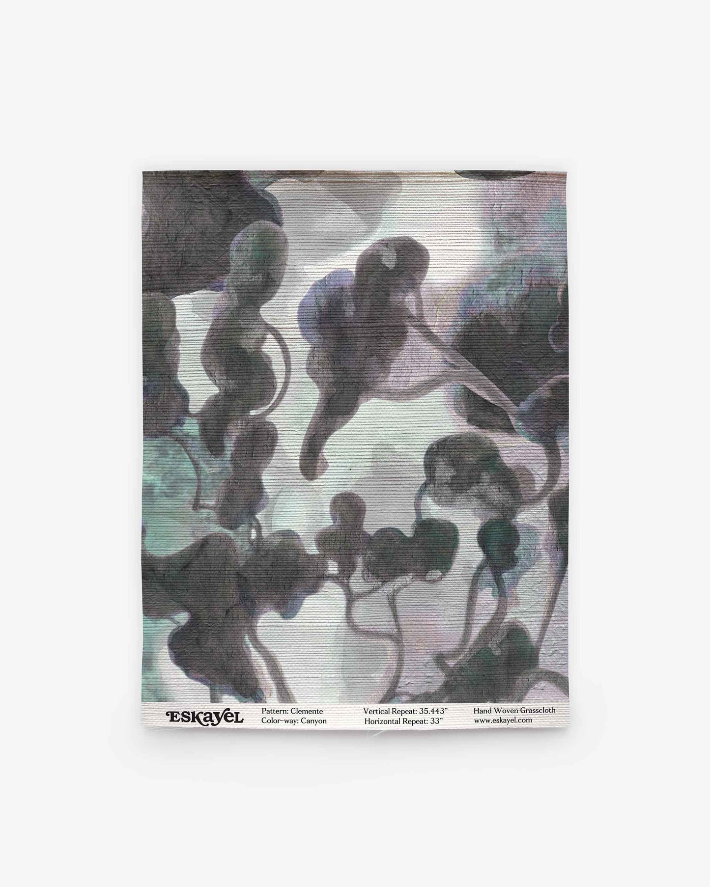 A square fabric swatch features an abstract, cloud-like watercolor pattern in muted gray, green, and purple tones on a light background, evoking the refined style of the Clemente Grasscloth||Canyon collection. Subtle text details and logo appear along the bottom edge, highlighting its inspiration from custom grasscloth wallpaper designs with abstracted tree motifs.