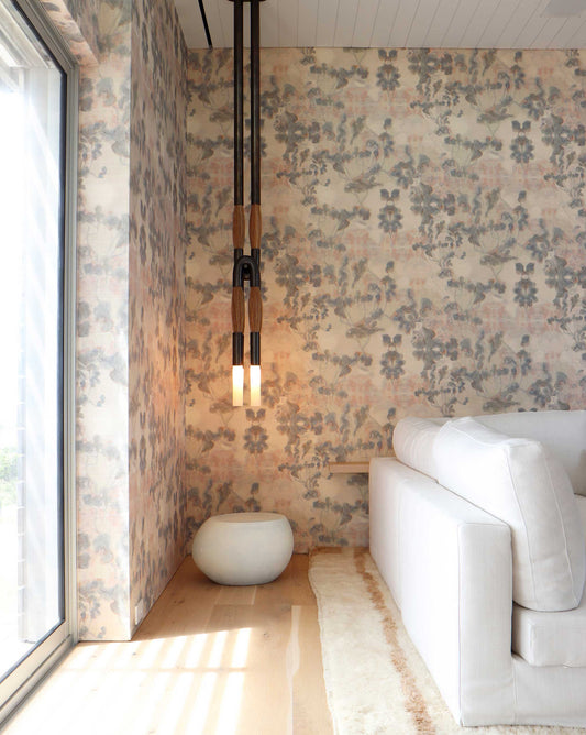 A modern living room features high-end custom Clemente Grasscloth wallpaper from the Sol Collection, a white couch, hanging pendant lights, and a round white stool placed next to a large glass window.