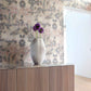 Vase with purple flowers on a wooden credenza against Eskayel's Clemente grasscloth wallpaper in sol.
