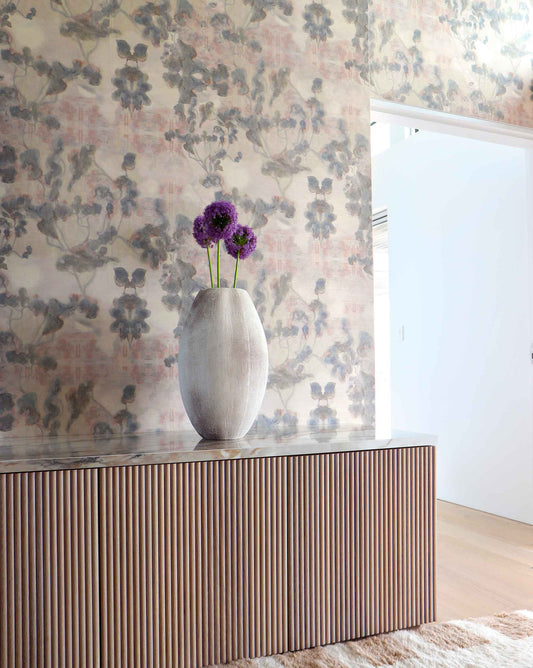 Vase with purple flowers on a wooden credenza against Eskayel's Clemente grasscloth wallpaper in sol.