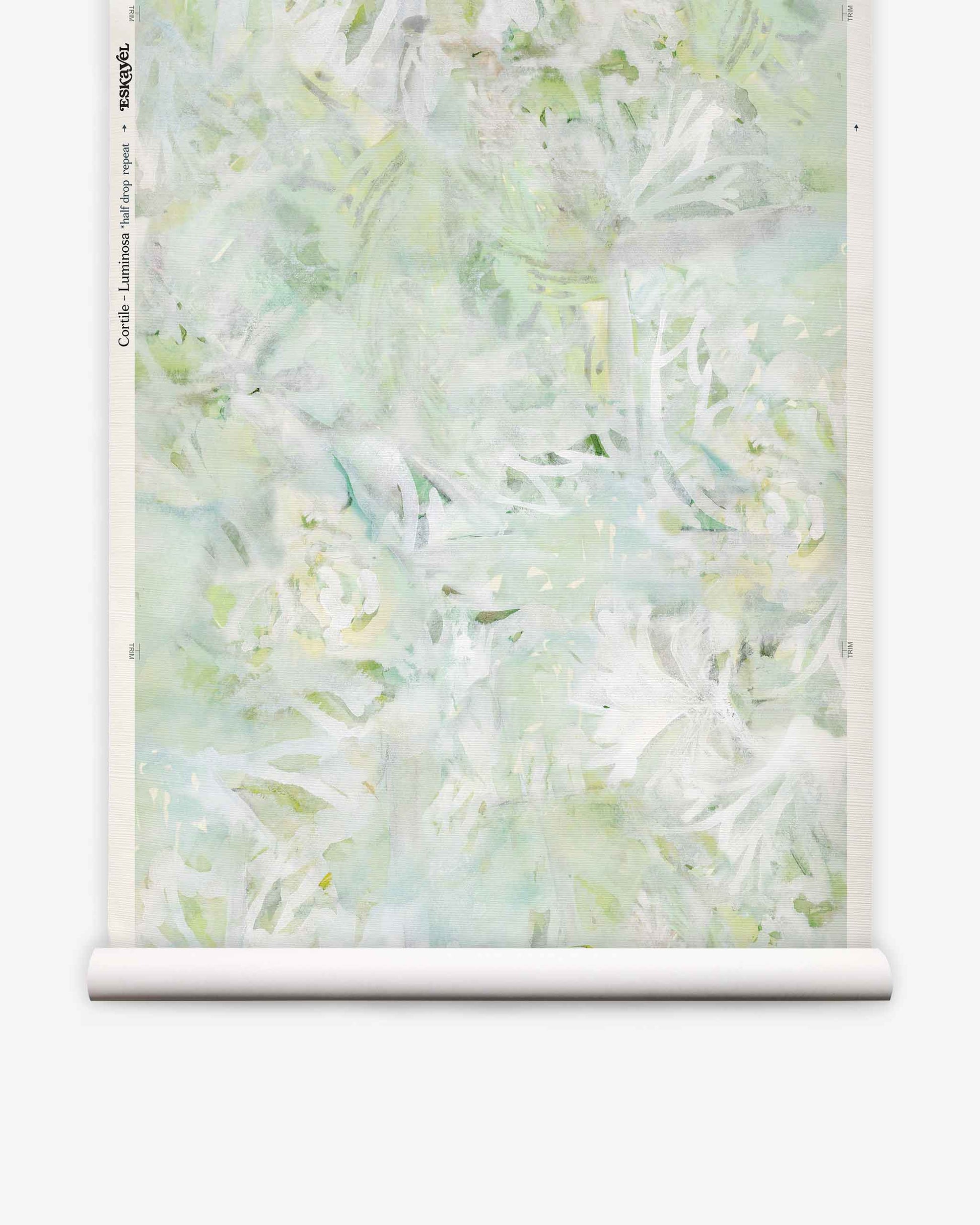 A partially unrolled roll of Cortile Grasscloth||Luminosa wallpaper, featuring a pastel green and white abstract floral design reminiscent of delicate watercolor, displayed against a white background.