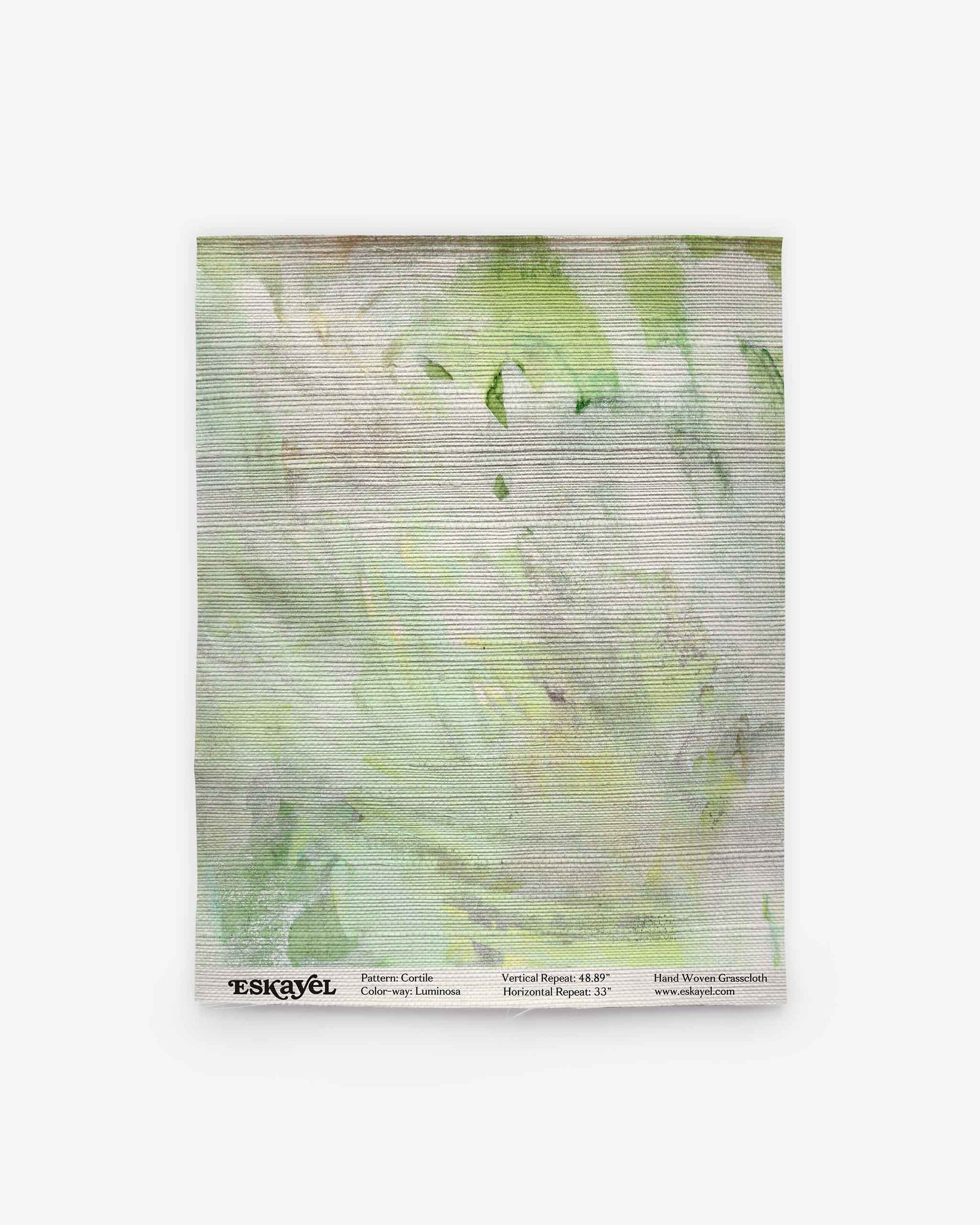 A square towel from the Cortile Grasscloth||Luminosa collection, featuring a light green and white watercolor pattern with horizontal textured lines and text along the bottom edge.