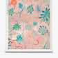 Introducing Edera Grasscloth||Stucco: a pastel pink wallpaper featuring a botanical pattern of green and blue tropical leaves with thin, winding vines reminiscent of ivy, accented by orange and yellow highlights—a fresh interpretation of modern chinoiserie wallpaper.