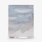 The Empyrean Grasscloth Sample||Air showcases a square textile with a woven abstract pattern of gray and blue clouds. Branding and website details are printed along the bottom edge. Order a sample to experience its unique texture and artistry firsthand.