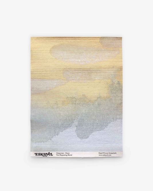 A rectangular mural featuring horizontal brushstrokes in shades of beige, yellow, gray, and blue. “Empyrean Grasscloth Sample || Dawn” from ESKAYEL with product details is printed along the bottom edge. Order a sample to experience the colors and textures firsthand.