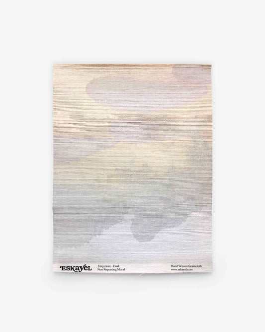 Experience the subtle elegance of the Empyrean Grasscloth Sample in Dusk—a square fabric featuring a muted watercolor-style pattern in beige, gray, and pale lavender tones. Branding and care details are printed along the bottom edge in small black text. Order your sample to appreciate this refined design firsthand.