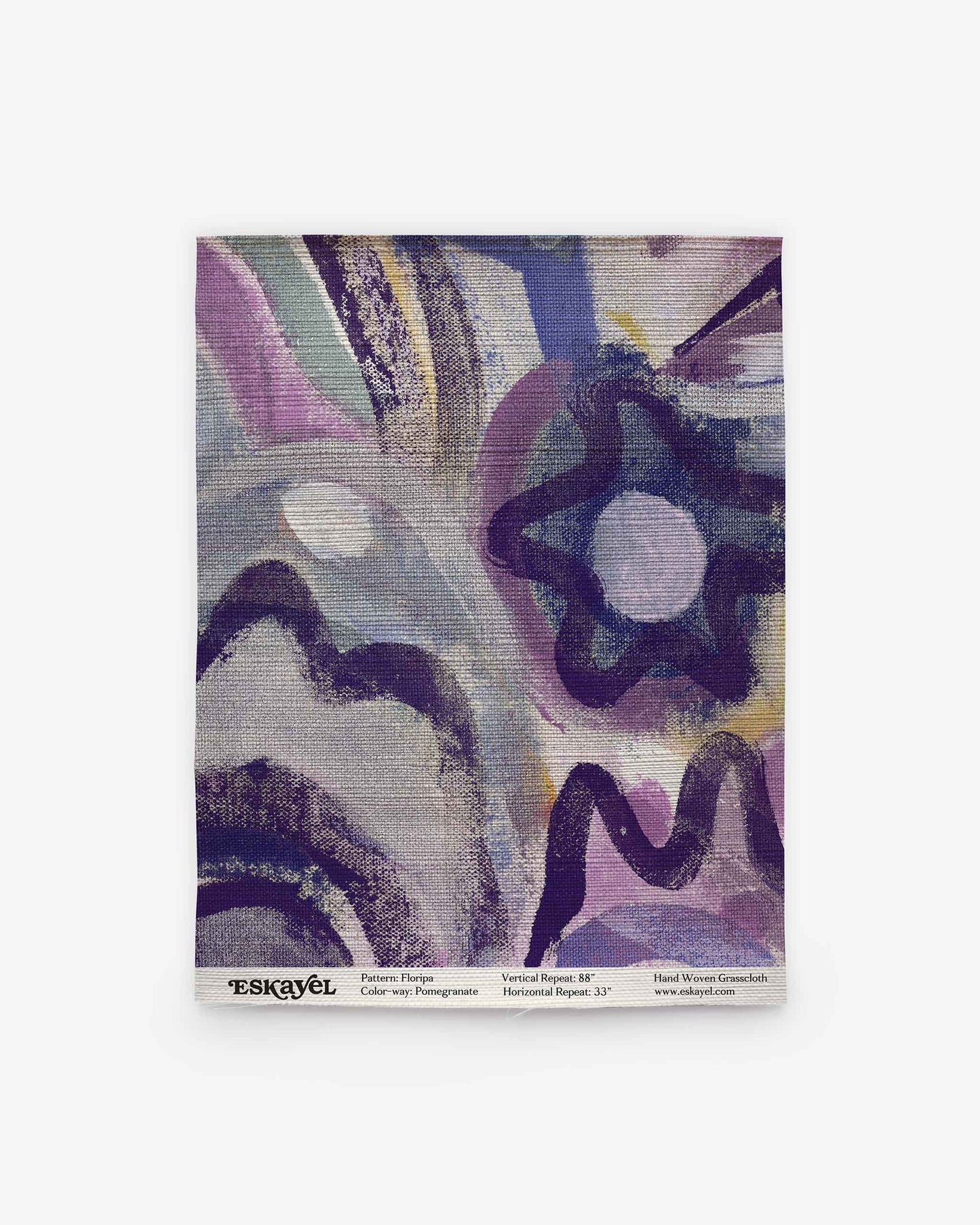 A sample of the Floripa Grasscloth in Pomegranate is displayed on a white background, showcasing its abstract purple, blue, and yellow pattern. Text at the bottom reads “ESKAYEL” along with design and size details. Order a sample to experience the unique quality and vibrant colors for yourself.