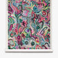 Floripa Grasscloth||Punch showcases a colorful abstract design with swirling, layered shapes and brushstrokes in pink, green, purple, and blue tones on a white scroll background; this striking piece evokes the luxurious look of high-end wallpaper.
