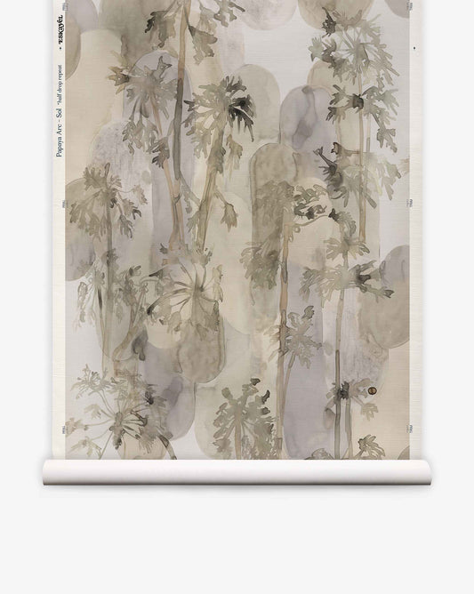Papaya Arc Grasscloth wallpaper roll featuring a hand-painted botanical pattern of papaya trees layered over soft, rounded gray shapes.