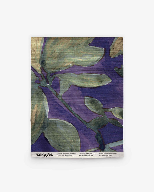 Square swatch of fabric featuring the Plumeria Shadows Grasscloth pattern in Eggplant, with abstract floral designs in green and purple hues. The bottom edge is marked with “ESKAYEL” and includes pattern and dimension details. Perfect for exploring your next project—Order a sample to experience the unique texture and vibrant colors firsthand.