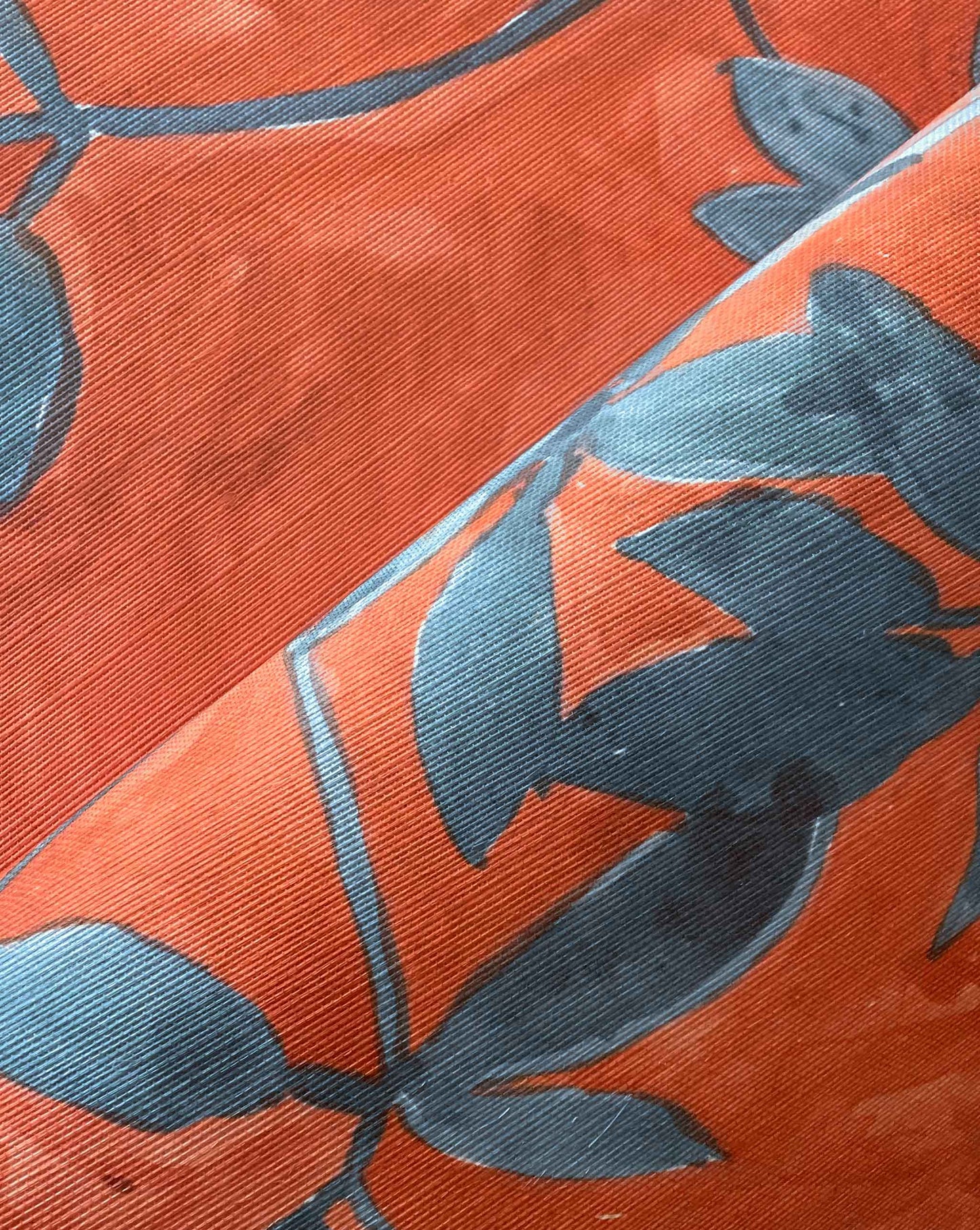 A detail crop shot of Eskayel’s Plumeria Shadows grasscloth wallpaper pattern in Hibiscus, a colorway with a rich red background.