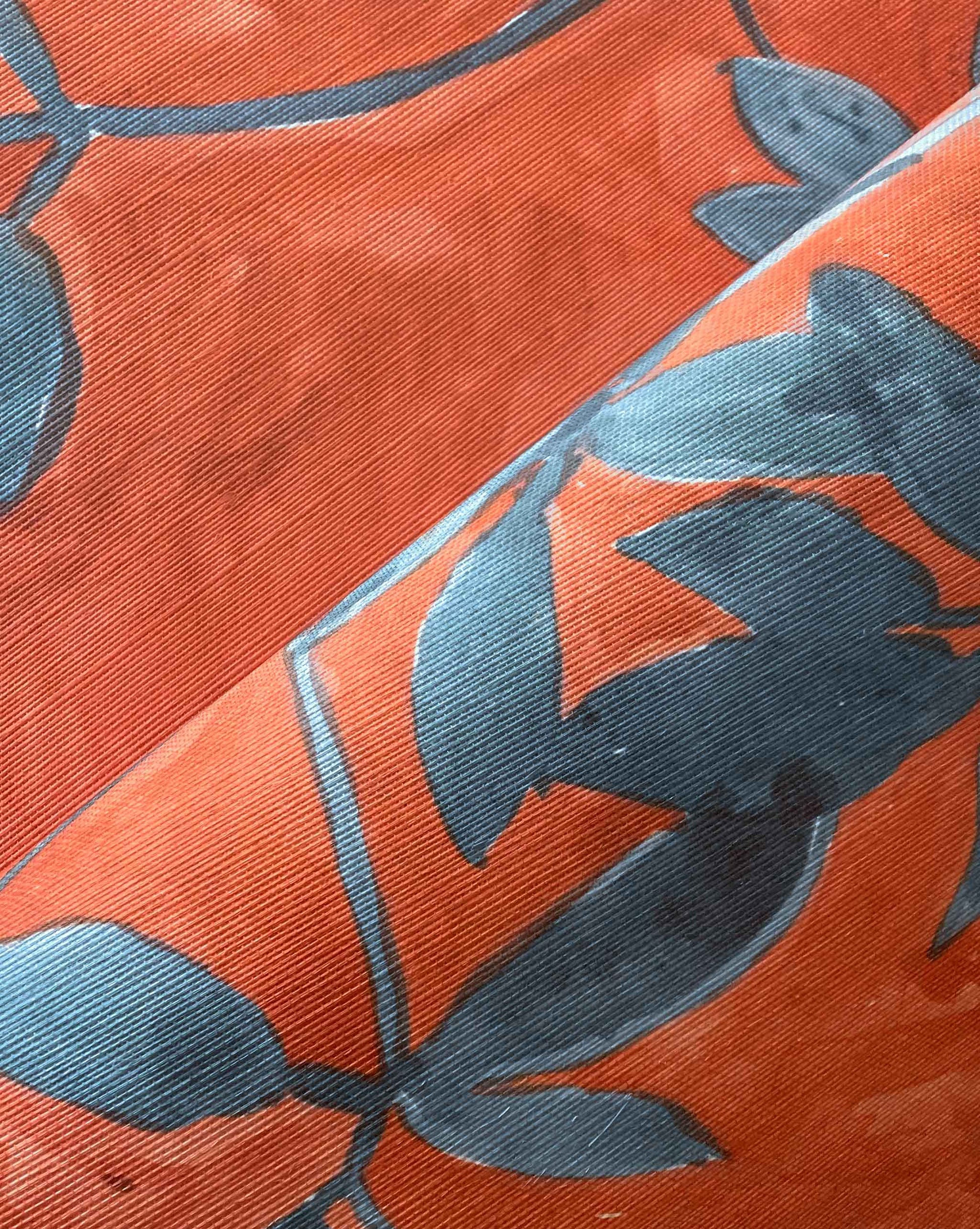 A detail crop shot of Eskayel’s Plumeria Shadows grasscloth wallpaper pattern in Hibiscus, a colorway with a rich red background.