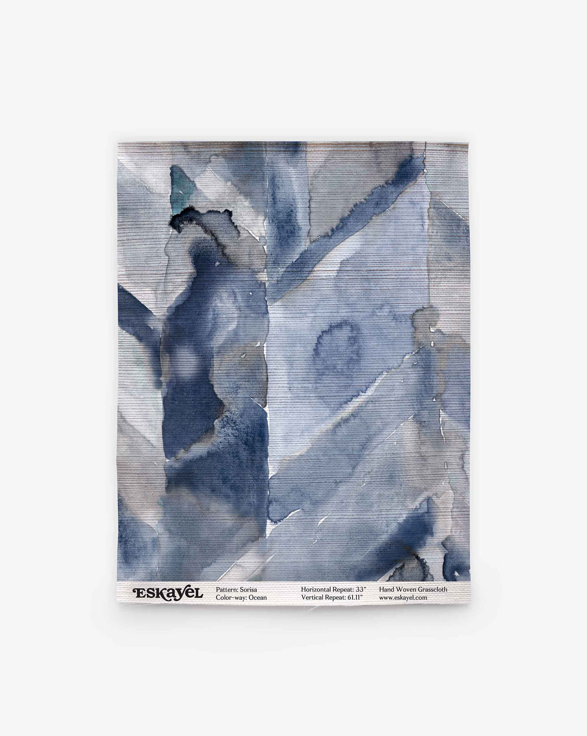 Abstract blue and gray watercolor textile swatch with overlapping geometric shapes evokes hand-woven wallpaper. Label: “Sorisa Grasscloth||Ocean” with pattern, color, and website details.