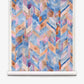 Sorisa Grasscloth||Reef features a watercolor-style geometric chevron pattern in blue, pink, purple, and orange on a rolled sheet of paper.