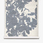The Up for Anything Grasscloth||Cerulean wallpaper roll features a large, abstract blue-gray floral pattern on a light background, unrolled and displayed vertically to showcase its sophisticated watercolor effect and abstract botanical design.