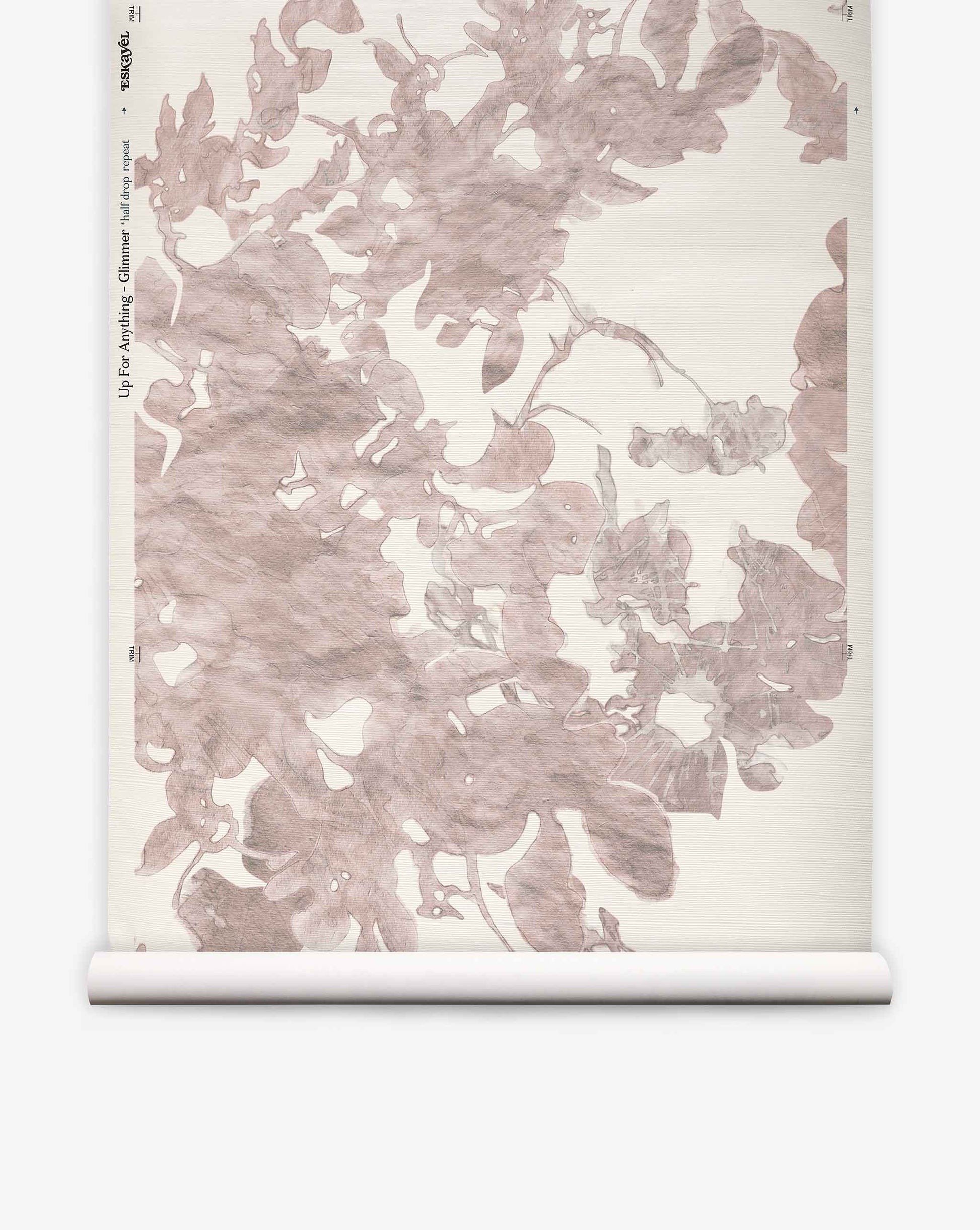 A roll of Up for Anything Grasscloth||Glimmer wallpaper features an Eskayel-inspired abstract botanical pattern in muted pink and beige tones on a light background.