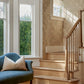 A wooden staircase by two large windows with white trim; a blue upholstered chair with a beige pillow sits in the foreground, accented by Up for Anything Grasscloth||Pearl wallcovering that adds texture to the space.