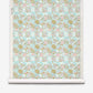 A roll of Yaya Grasscloth||Brisa wallpaper featuring a repeating pattern of abstract gold, pink, and light blue shapes set against a textured, grid-like sisal grasscloth background.
