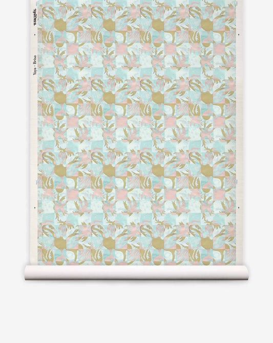 A roll of Yaya Grasscloth||Brisa wallpaper featuring a repeating pattern of abstract gold, pink, and light blue shapes set against a textured, grid-like sisal grasscloth background.