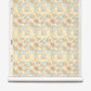 A roll of Yaya Grasscloth||Husk wallpaper featuring a repeating geometric pattern of interlocking tan, light blue, and cream shapes with a textured, hand-woven sisal grasscloth finish.