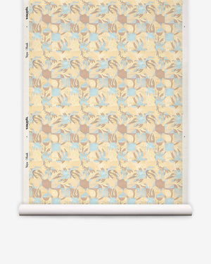 A roll of Yaya Grasscloth||Husk wallpaper featuring a repeating geometric pattern of interlocking tan, light blue, and cream shapes with a textured, hand-woven sisal grasscloth finish.