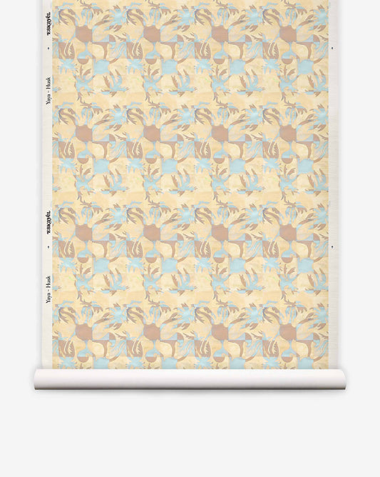 A roll of Yaya Grasscloth||Husk wallpaper featuring a repeating geometric pattern of interlocking tan, light blue, and cream shapes with a textured, hand-woven sisal grasscloth finish.