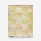 A rectangular Yaya Grasscloth Sample in Limeade featuring a lime green, yellow, and peach abstract patterned grasscloth wallpaper with product information printed along the bottom edge.