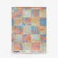 Yaya Grasscloth Sample in Punch, a rectangular piece of woven grasscloth featuring an abstract, grid-like pattern in watercolor shades of coral, blue, and peach.