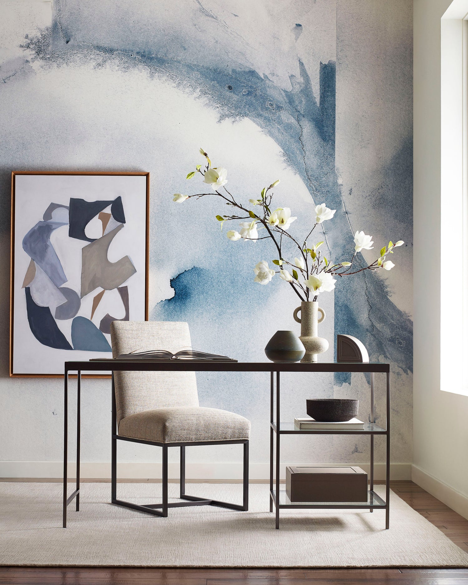 A room with a desk and a Mod Mural Wallpaper Indigo on the wall, featuring an abstract design