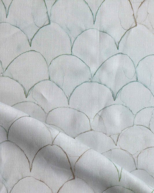 A close up of white fabric with fish scales on it, showcasing Baby Scallop Fabric||Sage.