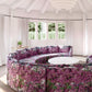 A living room with a circular couch and a coffee table adorned with Inflorescence Fabric Pomegranate geometric patterns