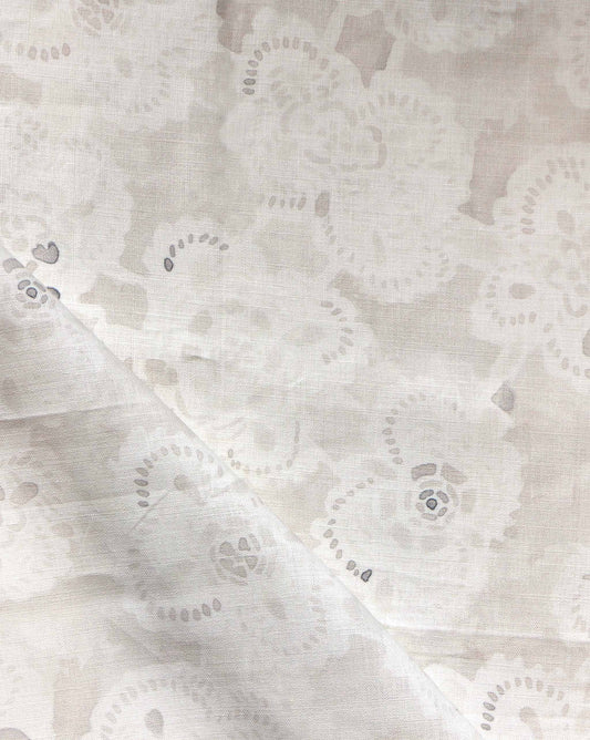 A close-up of Margherita Fabric||Ricotta, showcasing vintage handmade lace with a floral pattern and a diagonal fold across the lower left corner.