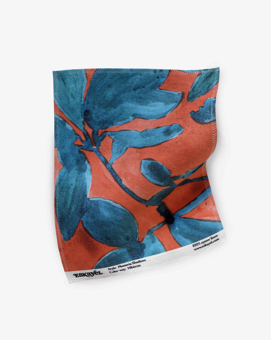 A fabric swatch of Plumeria Shadows in Hibiscus, a colorway featuring a rich red background | Eskayel