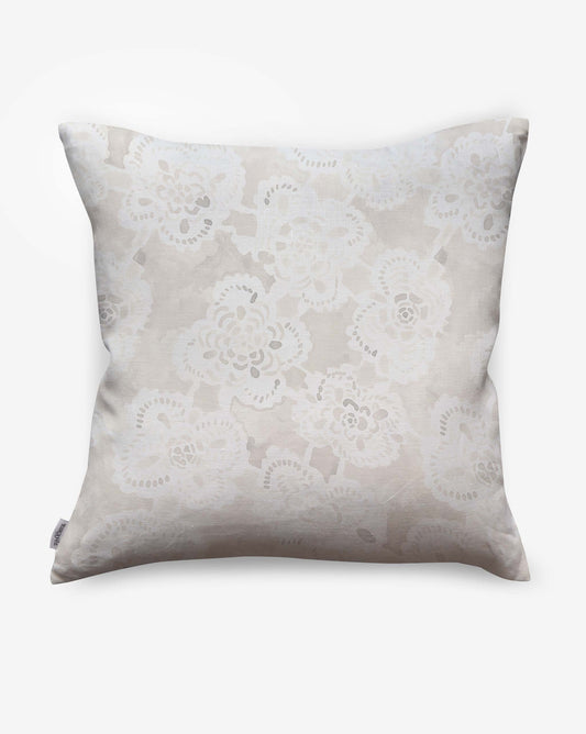 The Margherita Pillow||Ricotta features a light beige background with a delicate white floral pattern inspired by Italian lace, displayed on a plain white surface.