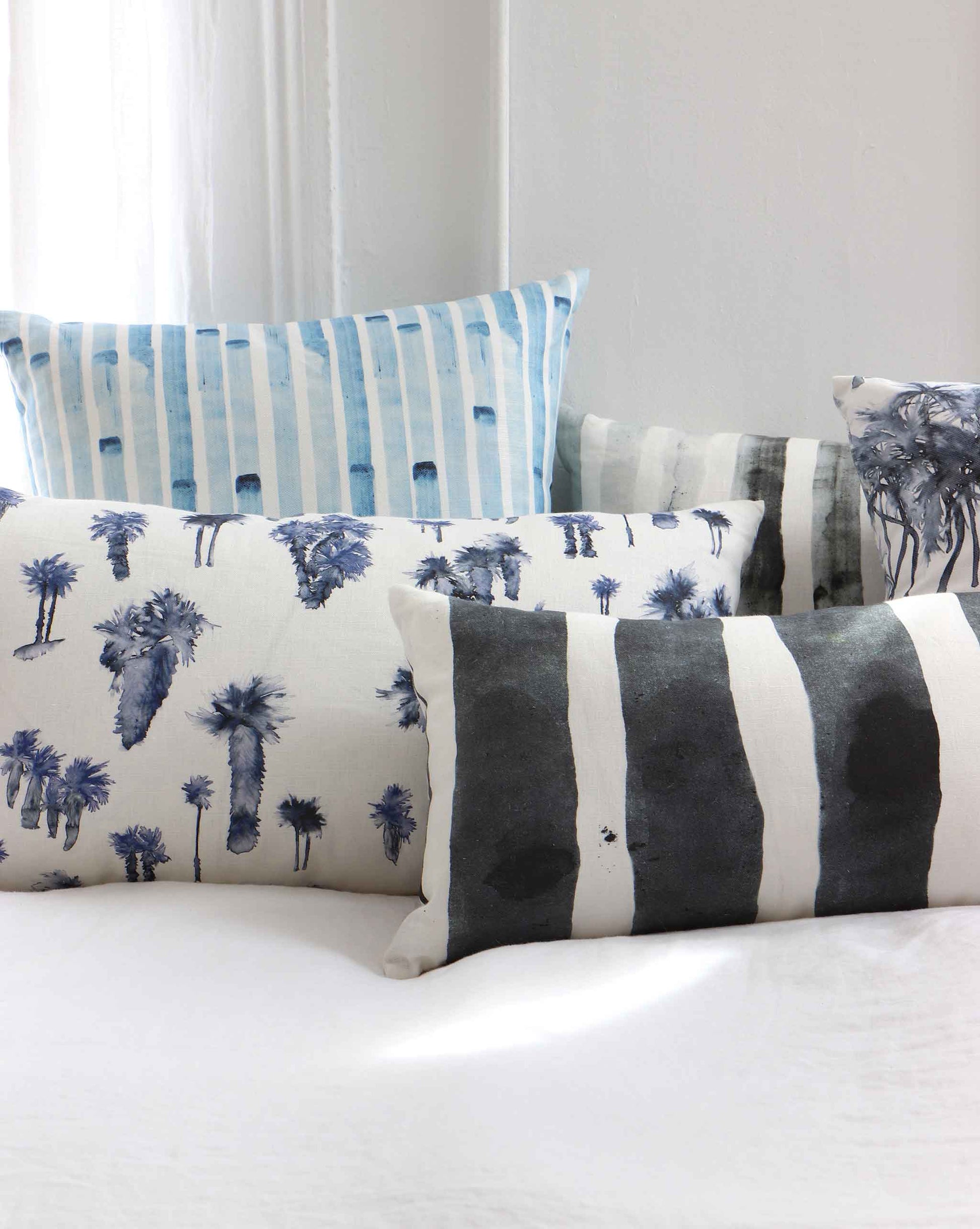Blue and white striped Custom Pillows in different designs on a bed