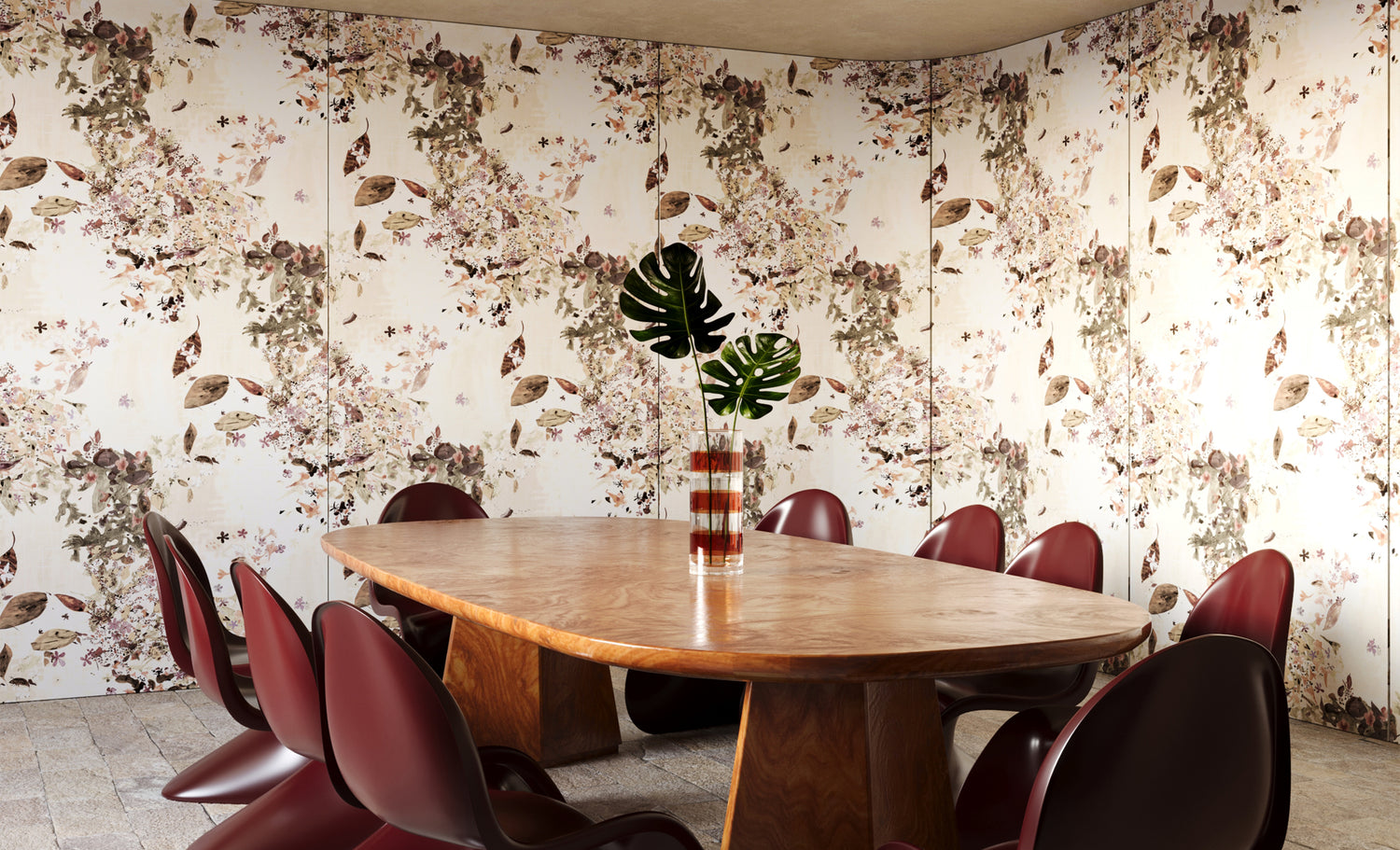 Warm wooden conference table with wine red chairs against Eskayel's Petalos wallpaper in Sand Dollar - a floral-patterned design in beige and warm toned neutrals.