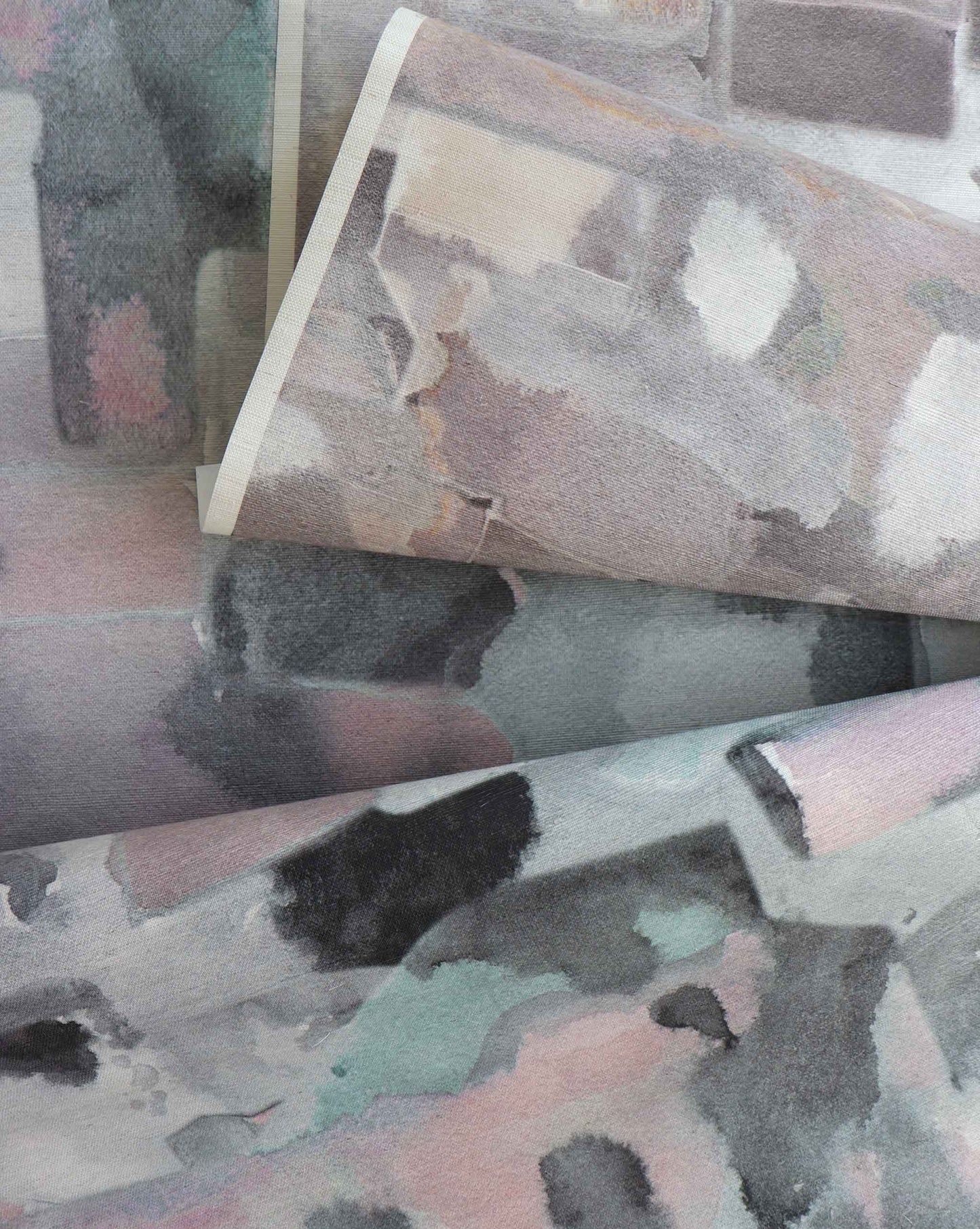 Close-up of overlapping Custom Grasscloth sheets featuring abstract, watercolor-like patterns in muted pastel and gray tones—ideal inspiration for unique wallpaper or custom design projects.