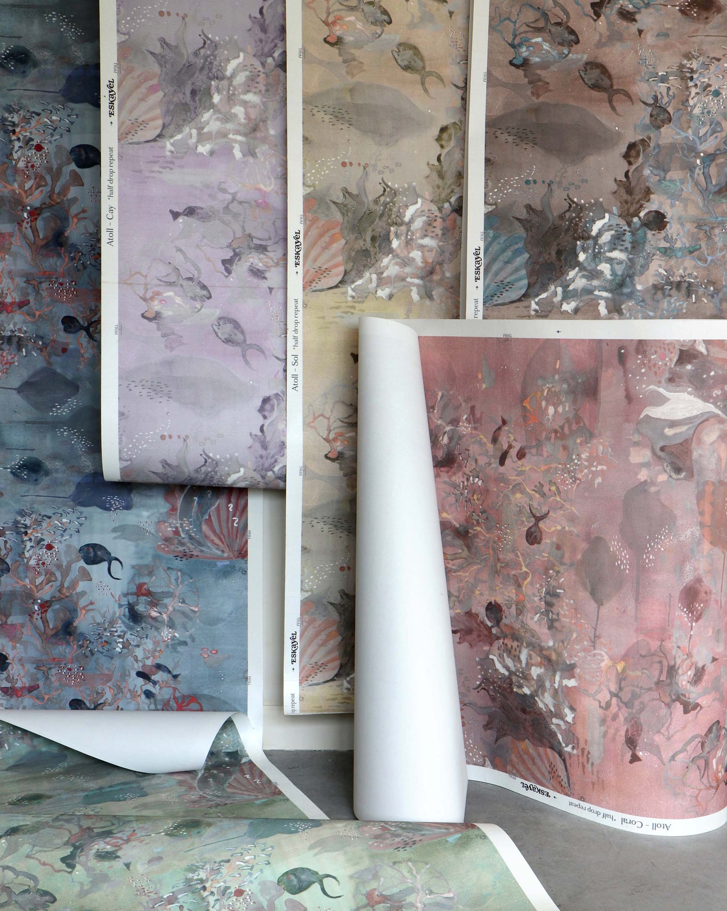 Sheets of Custom Silk Wallcovering samples with underwater-themed patterns in muted shades—blue, purple, brown, and pink—are displayed overlapping each other.