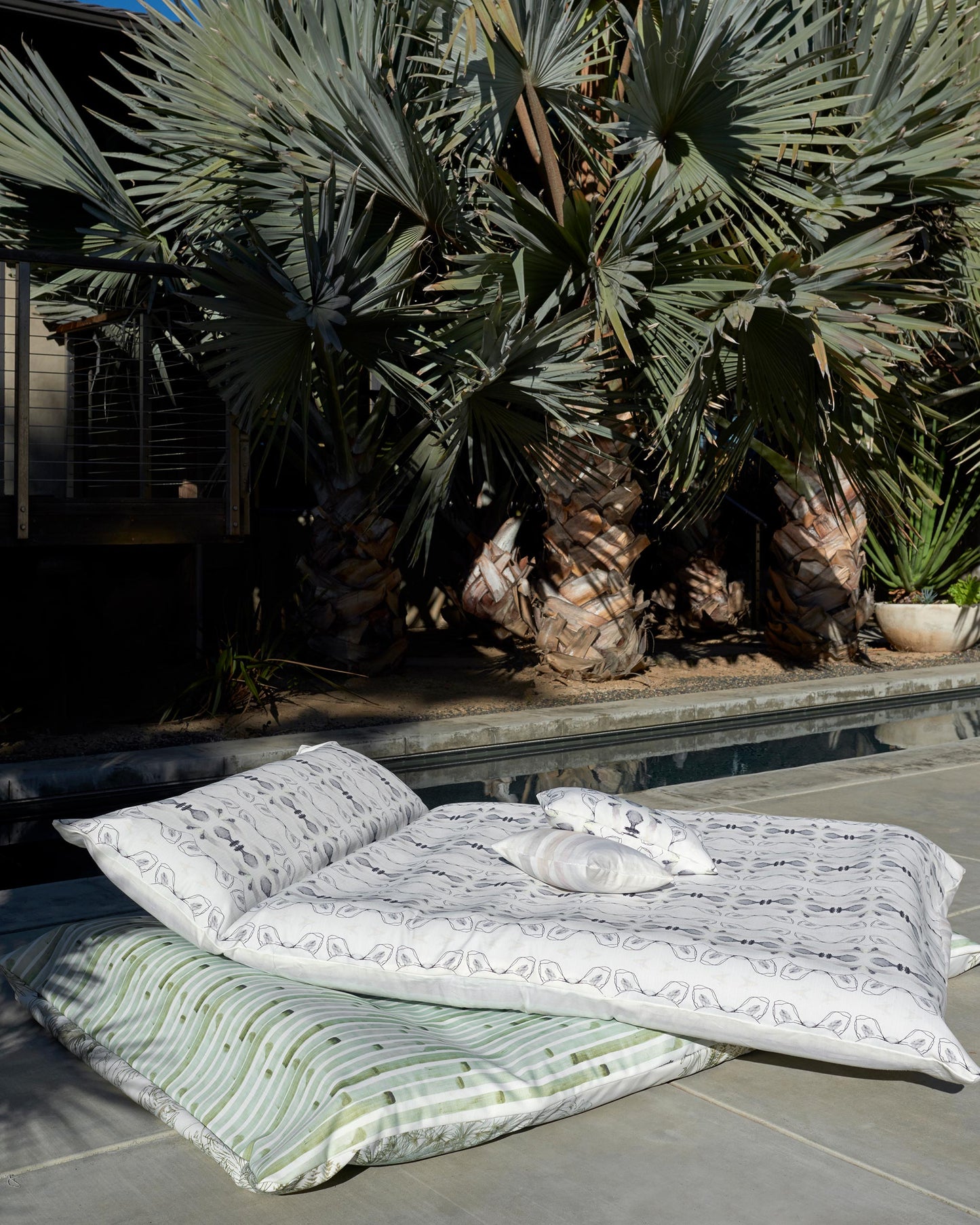 A Bali Stripe Performance Fabric Sand luxury pillow next to a palm tree in Bali