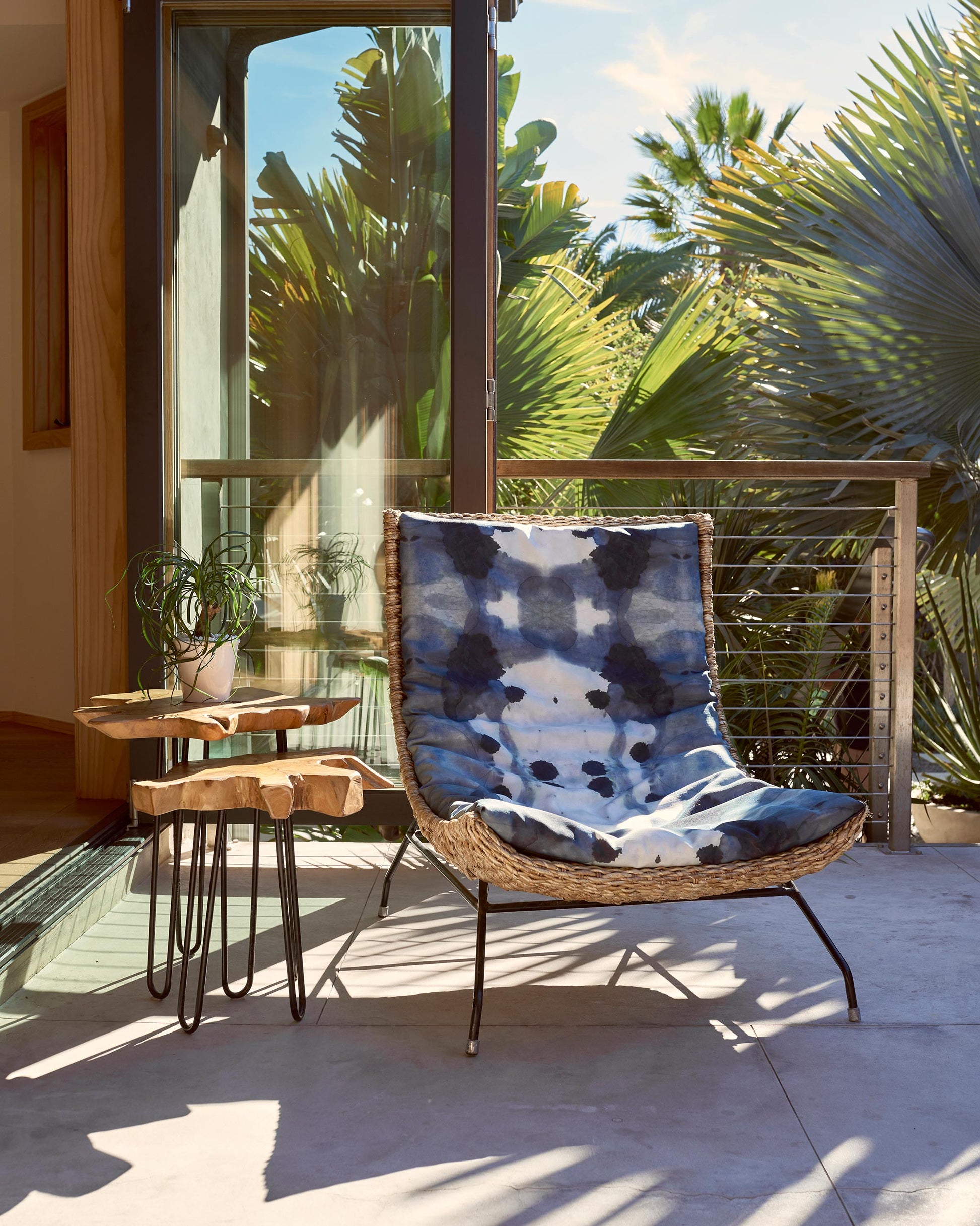 A luxurious Dynasty Performance Fabric||Indigo lounge chair on a Tuscany patio surrounded by palm trees.