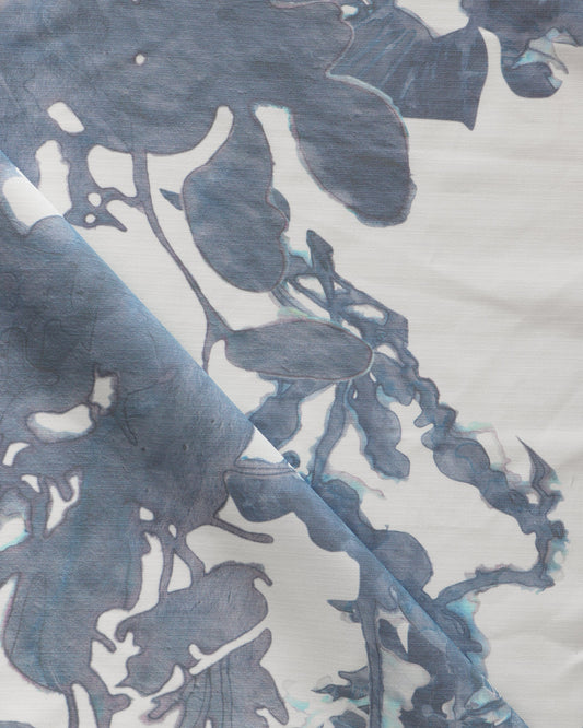 A close up of the Up for Anything Performance Fabric Cerulean, a luxury performance fabric with a blue and white abstract botanical pattern suitable for high-traffic applications