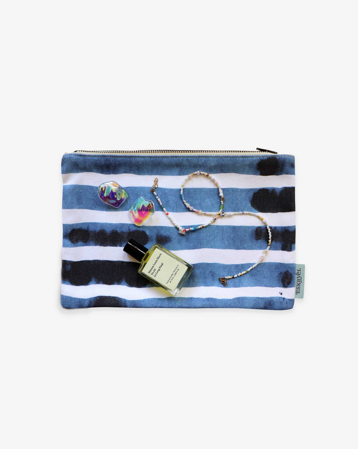 Pouch in our Bold stripe pattern in the colorway azure is displayed elegantly on a light background, demonstrating ideal purse organization. Inside, it contains a small perfume bottle, earrings, and a beaded necklace for your convenience.