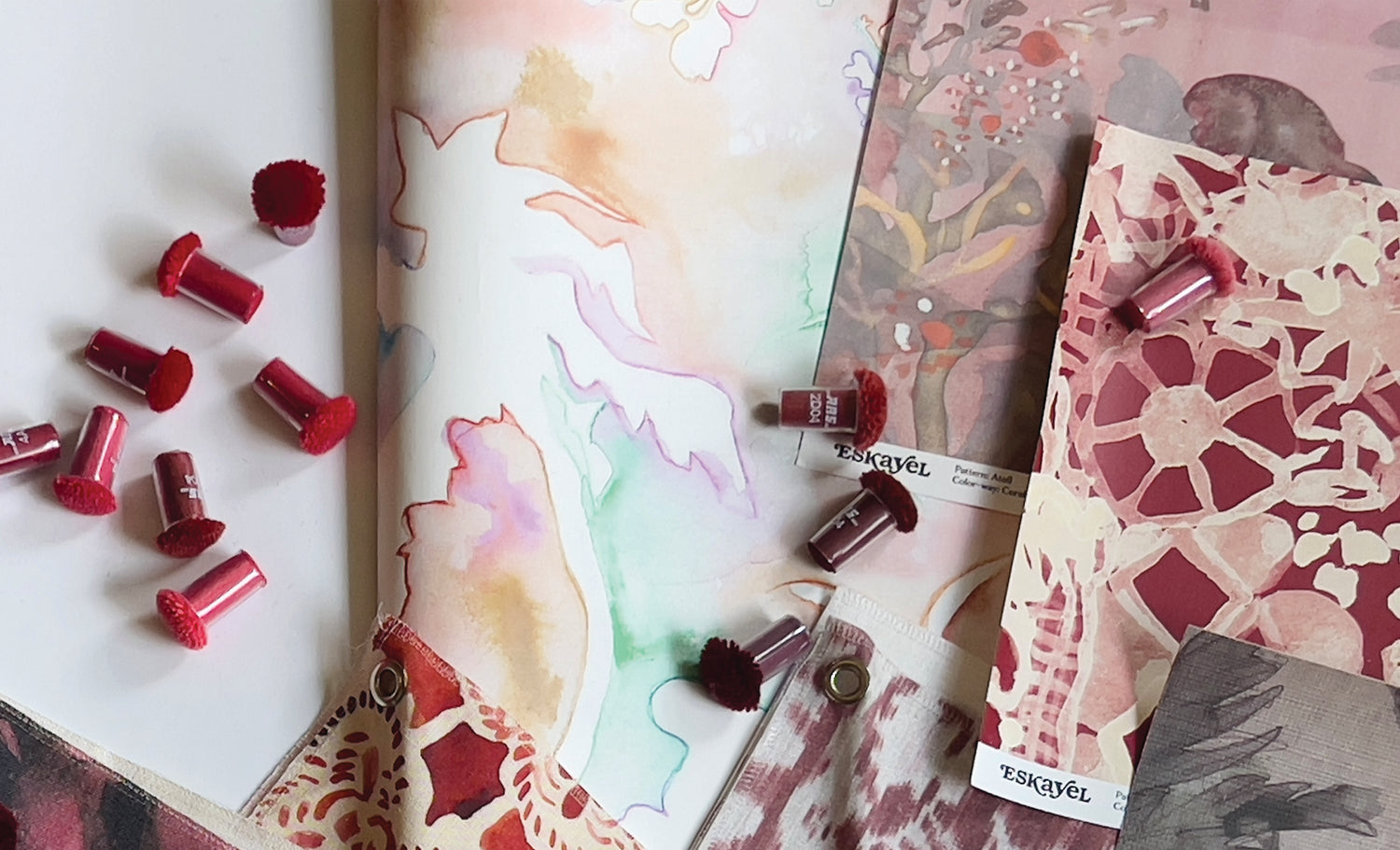 Red shades of wallpaper samples and rug poms