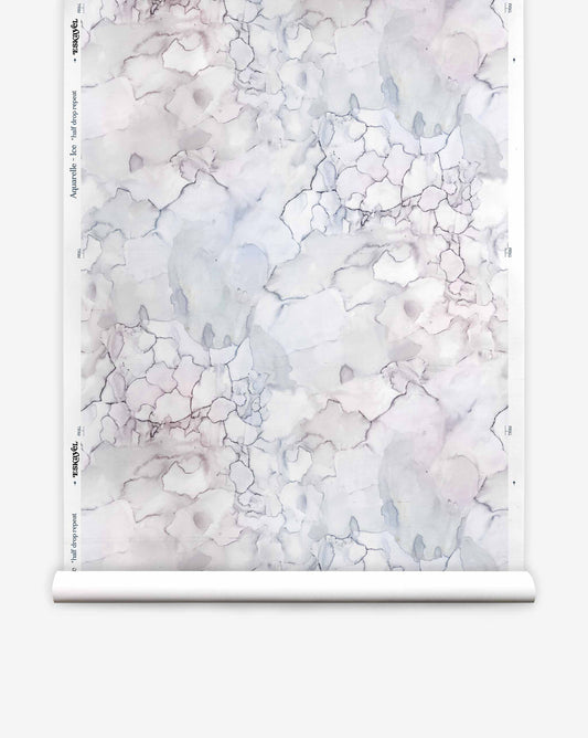 A roll of Aquarelle Silk Wallcovering in Ice, featuring a pale, marbled watercolor pattern in shades of grey, blue, and violet.