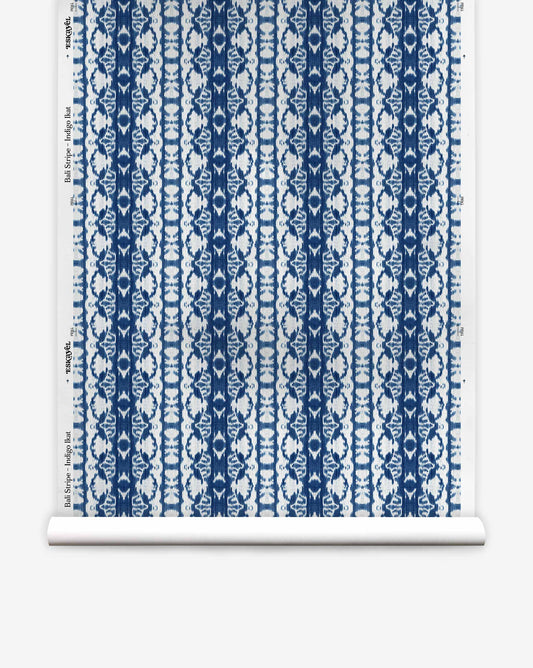 A roll of Bali Stripe Silk Wallcovering in Indigo Ikat, featuring a vertical indigo and white stripe pattern.