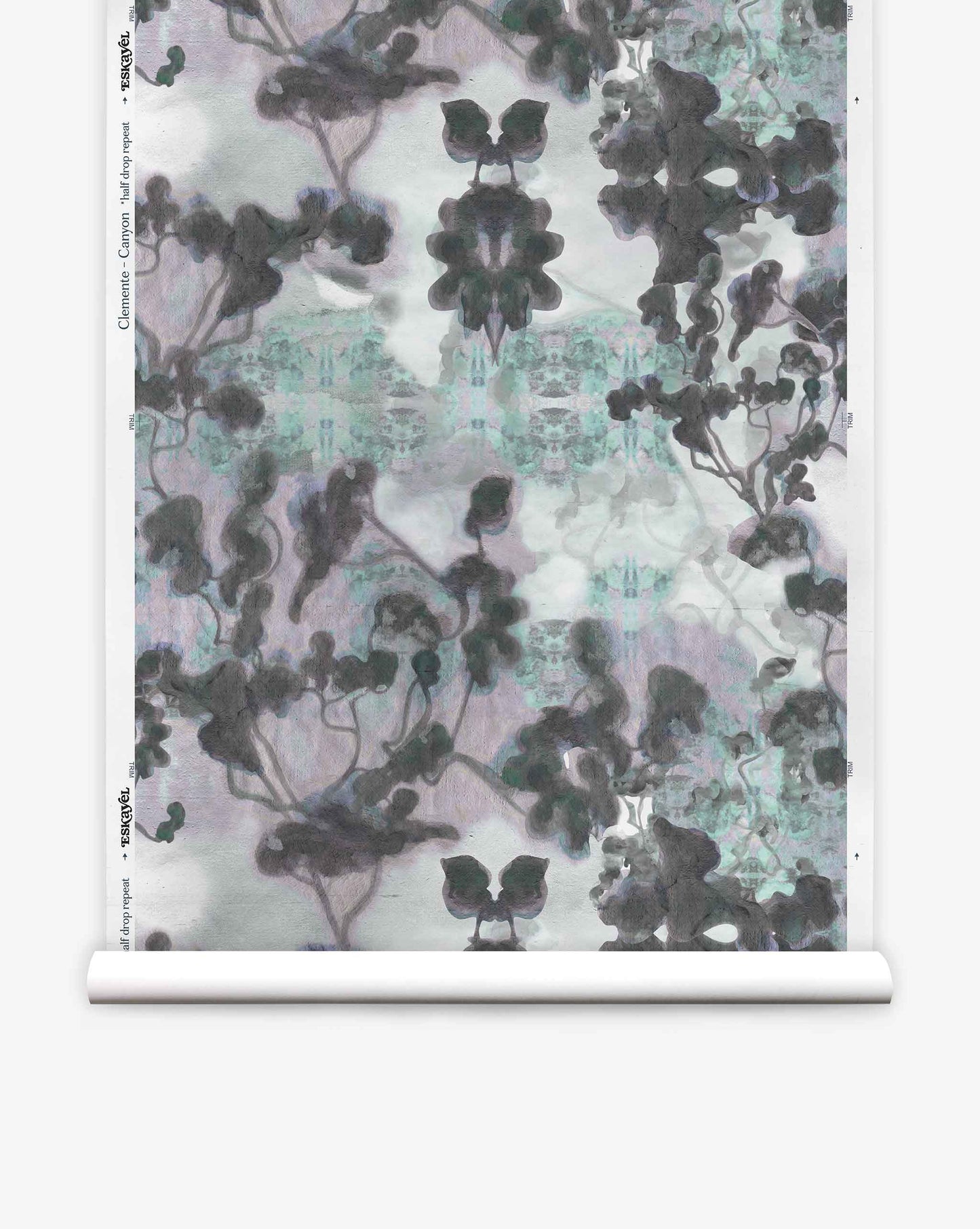 A roll of Clemente Silk Wallcovering in the Canyon colorway features an abstract, symmetrical pattern in shades of black, gray, and light blue with organic, cloud-like shapes. This custom wallcovering adds a modern touch to any space while evoking the gentle fluidity of botanical wallpaper designs.